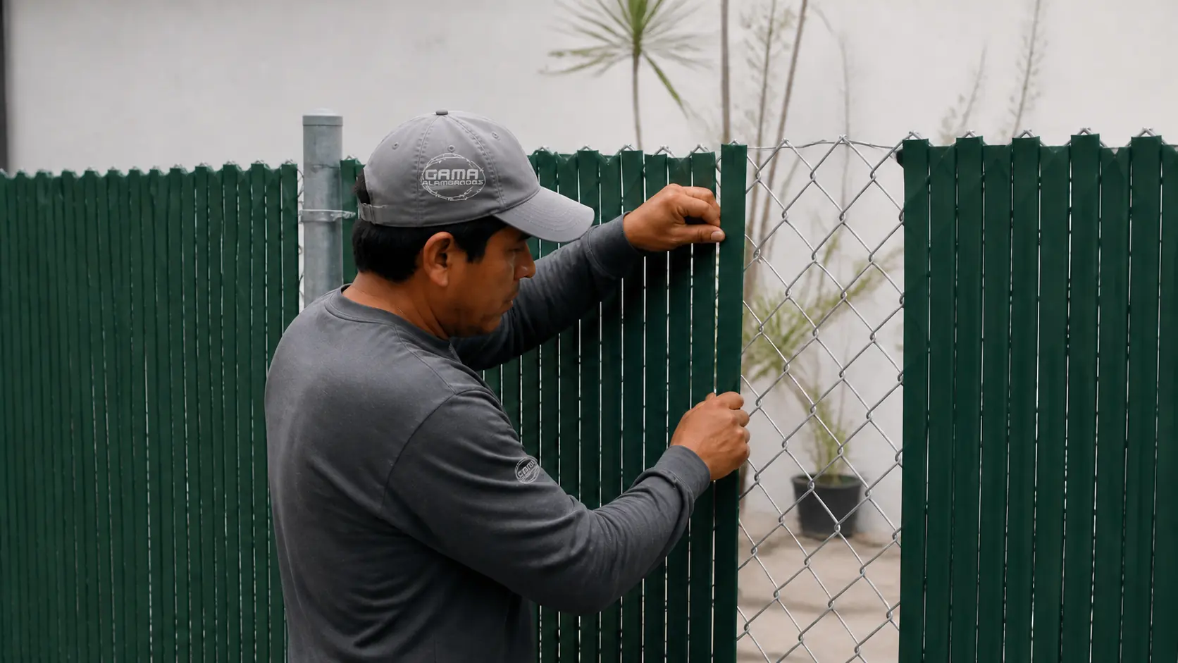 Instalador de Alambrados Gama colocando cinta de privacidad verde en malla ciclónica